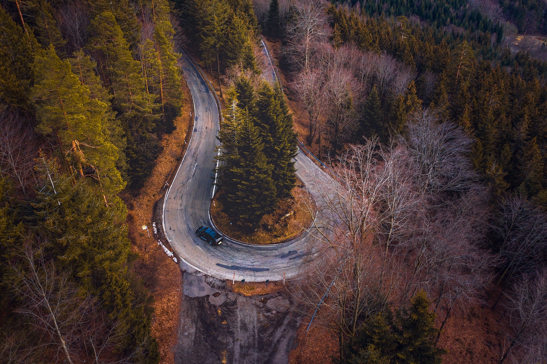 Luftaufnahme einer kurvenreichen Passstraße durch den Wald